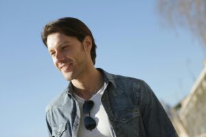 Smiling young man wearing casual wear and sunglasses outdoors on a sunny day.